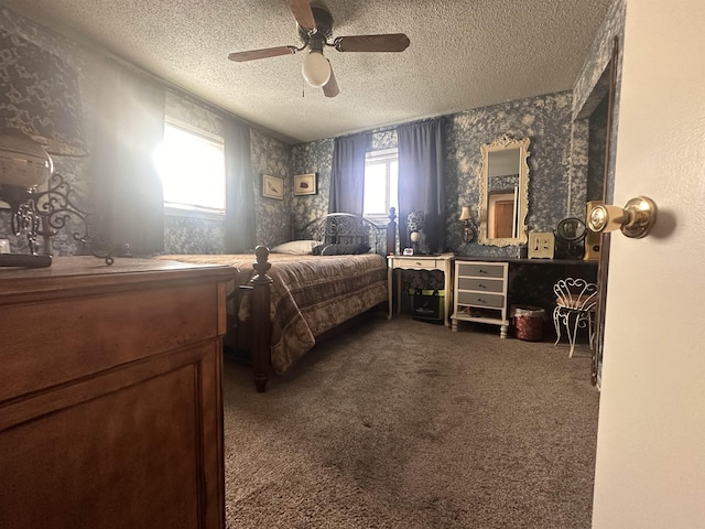 bedroom featuring wallpapered walls, ceiling fan, dark carpet, and a textured ceiling