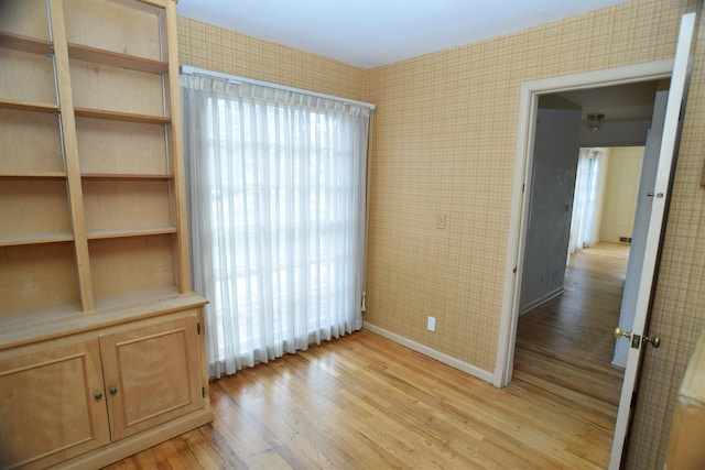 unfurnished room featuring light wood-type flooring and wallpapered walls