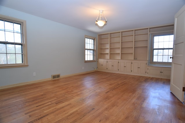 spare room featuring light wood finished floors, baseboards, and visible vents