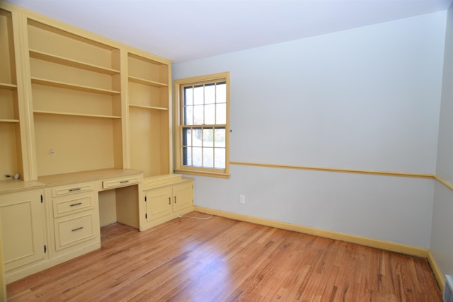 unfurnished office featuring visible vents, built in study area, light wood-style flooring, and baseboards