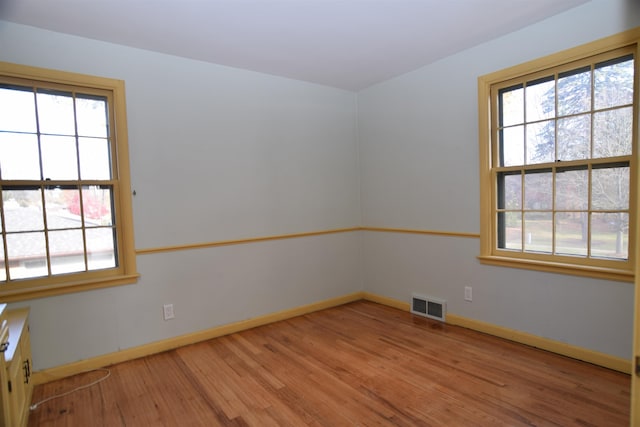 spare room featuring light wood-style flooring, visible vents, and baseboards