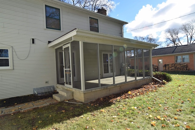 back of property featuring a sunroom, a lawn, and a chimney