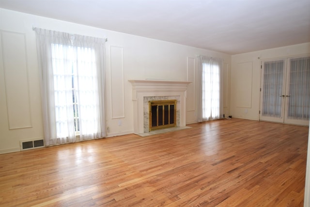 unfurnished living room featuring a healthy amount of sunlight, a fireplace, and light wood finished floors