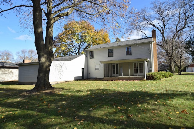 back of house with a sunroom, a chimney, and a lawn