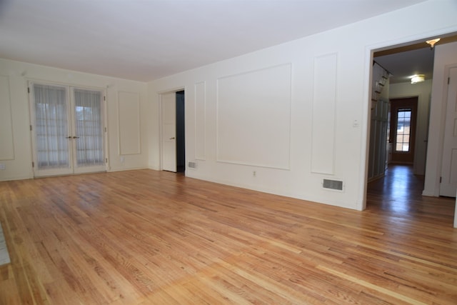 unfurnished room featuring visible vents, a decorative wall, and light wood-style flooring