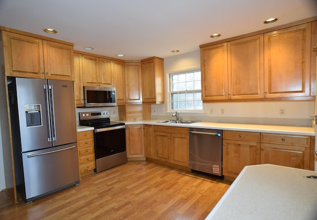 kitchen featuring appliances with stainless steel finishes, light countertops, light wood-style floors, a sink, and recessed lighting