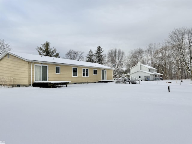 snow covered back of property with crawl space and a wooden deck