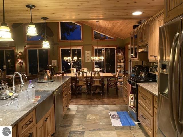 kitchen featuring a chandelier, lofted ceiling, wooden ceiling, under cabinet range hood, and appliances with stainless steel finishes