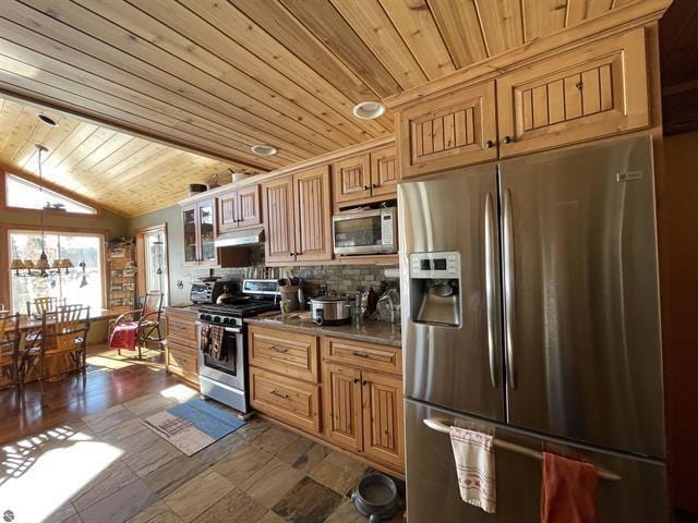 kitchen featuring lofted ceiling, wooden ceiling, under cabinet range hood, appliances with stainless steel finishes, and decorative backsplash