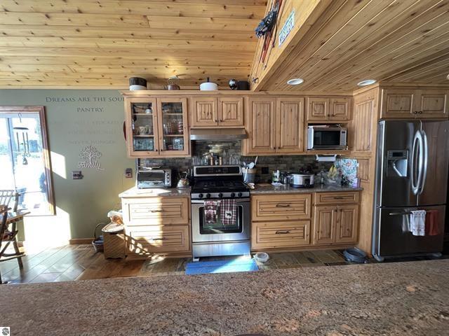 kitchen featuring decorative backsplash, wood ceiling, glass insert cabinets, appliances with stainless steel finishes, and under cabinet range hood