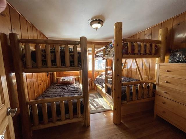 bedroom featuring wood walls, vaulted ceiling, and wood finished floors