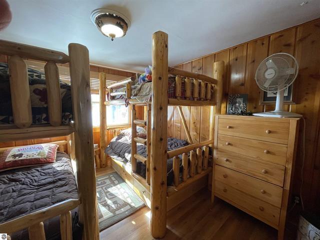 bedroom with wood walls and wood finished floors