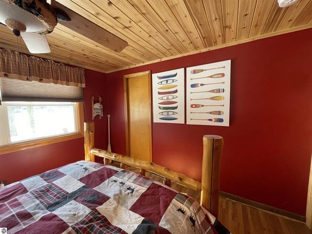 bedroom with wooden ceiling, baseboards, and wood finished floors