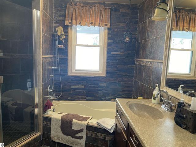 full bathroom with a bath, a shower stall, vanity, and tile walls