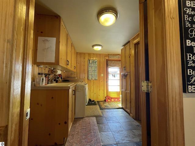 interior space featuring wooden walls, stone finish floor, a sink, and washer and dryer