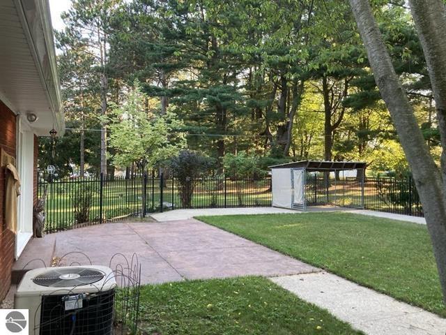 view of yard featuring fence, central AC unit, and a patio