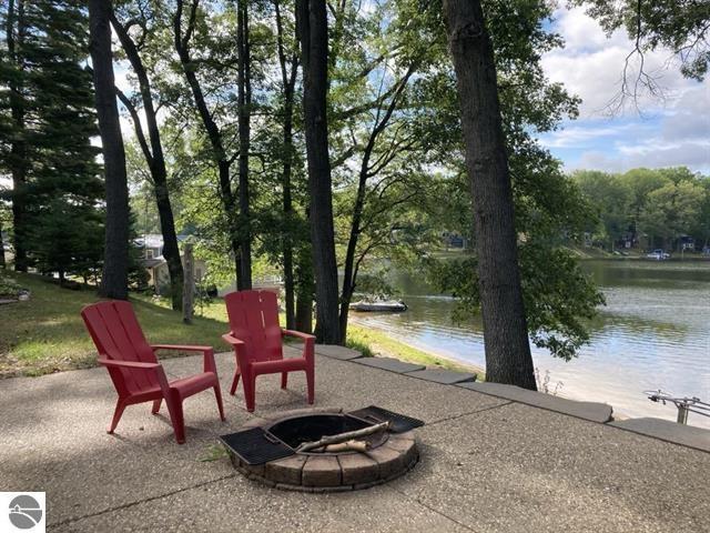 exterior space featuring a water view, an outdoor fire pit, and a patio