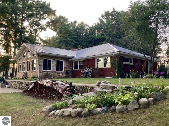 ranch-style house with stone siding, metal roof, and a front yard