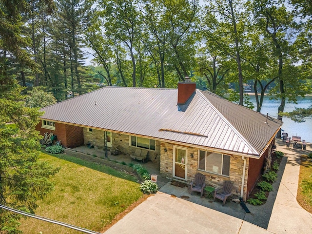 7836 W Perch Lake Dr, Lake, MI 48632 - view of front of property featuring stone siding, a chimney, a patio, and a water view