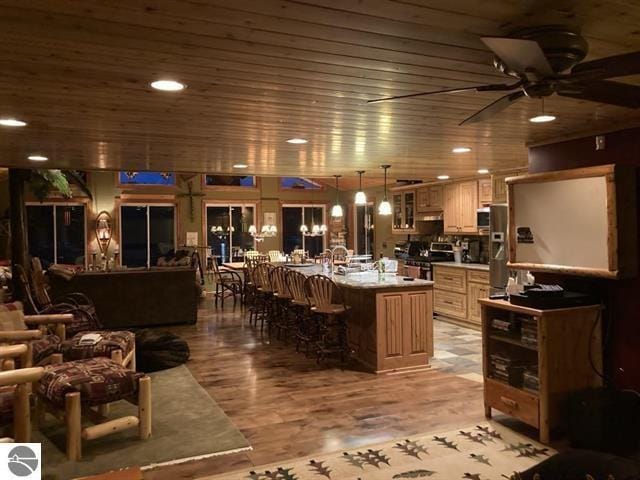 kitchen featuring appliances with stainless steel finishes, a breakfast bar area, light wood-style flooring, and wood ceiling