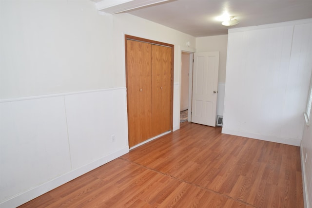 unfurnished bedroom featuring light wood-style floors, a closet, and visible vents