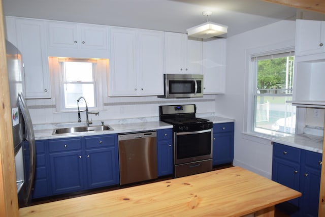 kitchen with appliances with stainless steel finishes, blue cabinets, and a sink