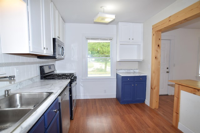 kitchen featuring appliances with stainless steel finishes, white cabinets, a sink, and blue cabinetry