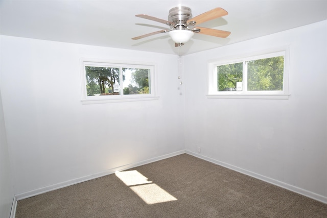 carpeted spare room featuring baseboards and a ceiling fan