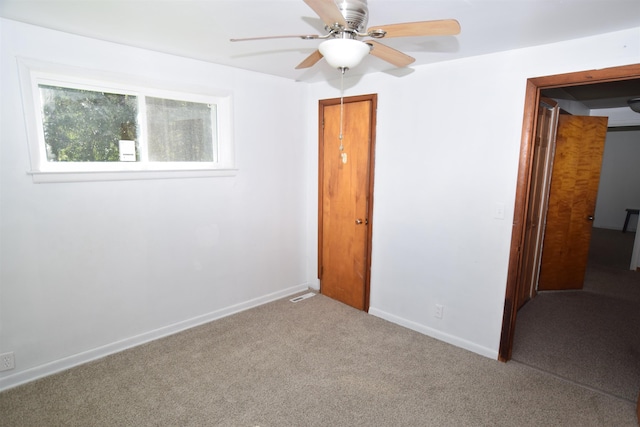 carpeted empty room with a ceiling fan and baseboards