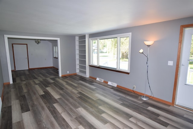 unfurnished living room featuring wood finished floors, visible vents, and baseboards