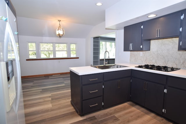 kitchen with black gas cooktop, tasteful backsplash, freestanding refrigerator, a sink, and a peninsula