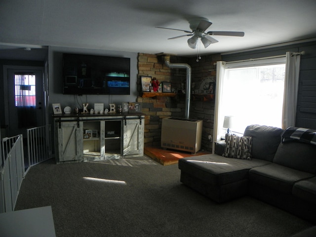 carpeted living area with a wood stove and ceiling fan