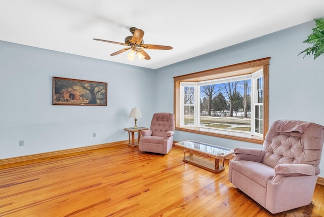 sitting room with ceiling fan, baseboards, and wood finished floors