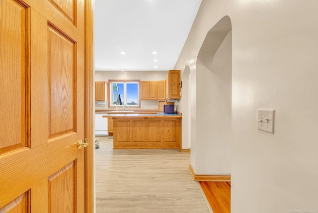 kitchen with arched walkways, recessed lighting, light countertops, light wood-style floors, and dishwasher