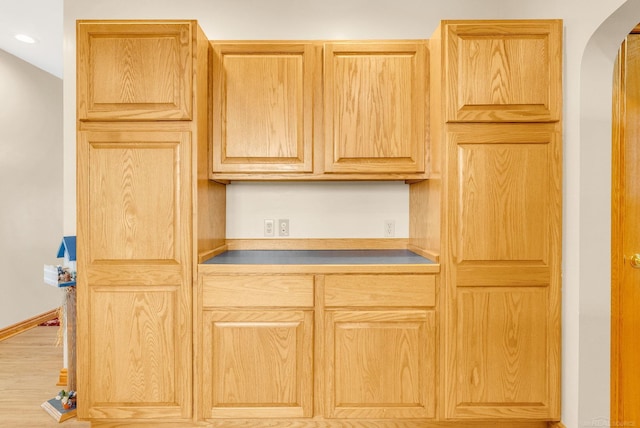 kitchen with arched walkways, recessed lighting, light brown cabinetry, wood finished floors, and baseboards