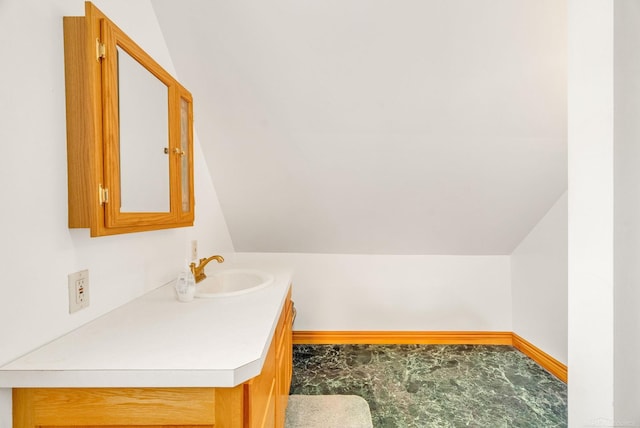 bathroom featuring vaulted ceiling, vanity, and baseboards