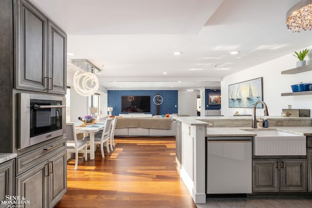 kitchen featuring light stone counters, recessed lighting, wood finished floors, a sink, and stainless steel dishwasher