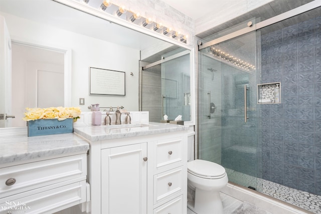 bathroom featuring toilet, a stall shower, and vanity