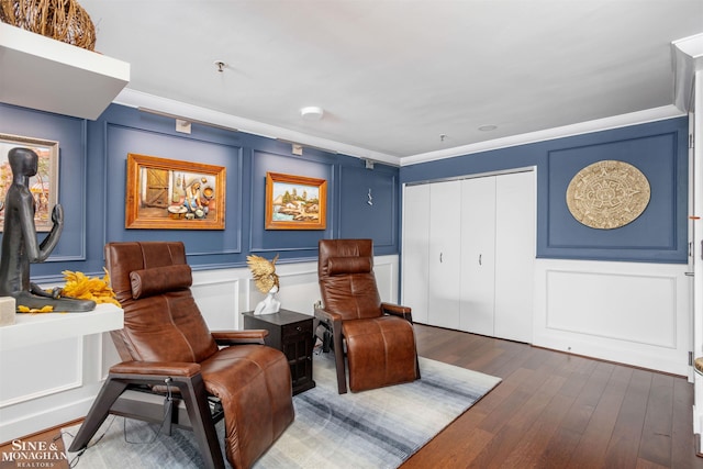 living area featuring ornamental molding, dark wood-type flooring, and a decorative wall