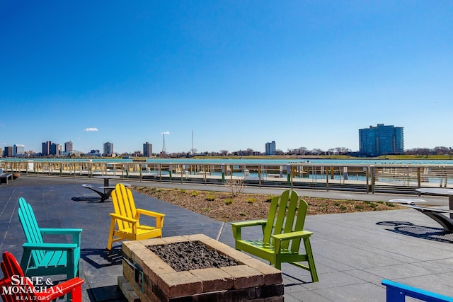 view of patio / terrace featuring a view of city, a water view, and a fire pit