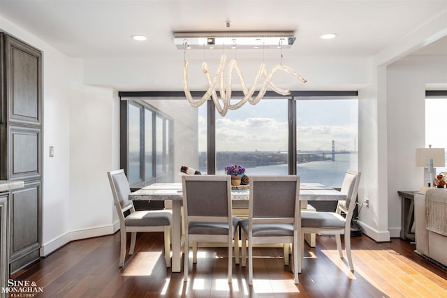 dining space with baseboards, dark wood-style flooring, a wealth of natural light, and a notable chandelier