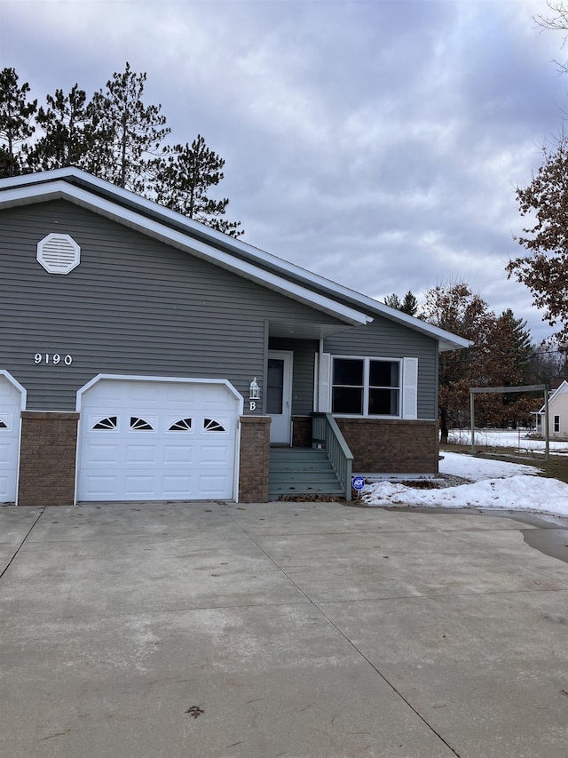 view of front of home featuring a garage, concrete driveway, and brick siding