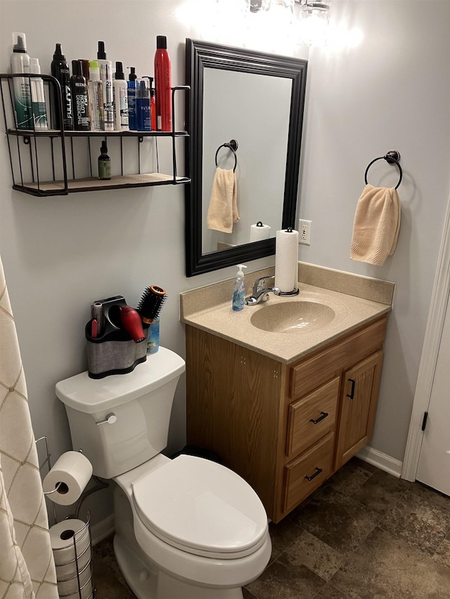 bathroom featuring toilet, baseboards, and vanity