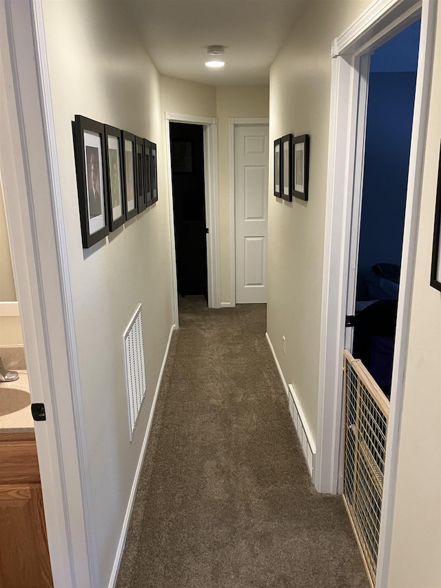 hallway with carpet floors, visible vents, and baseboards