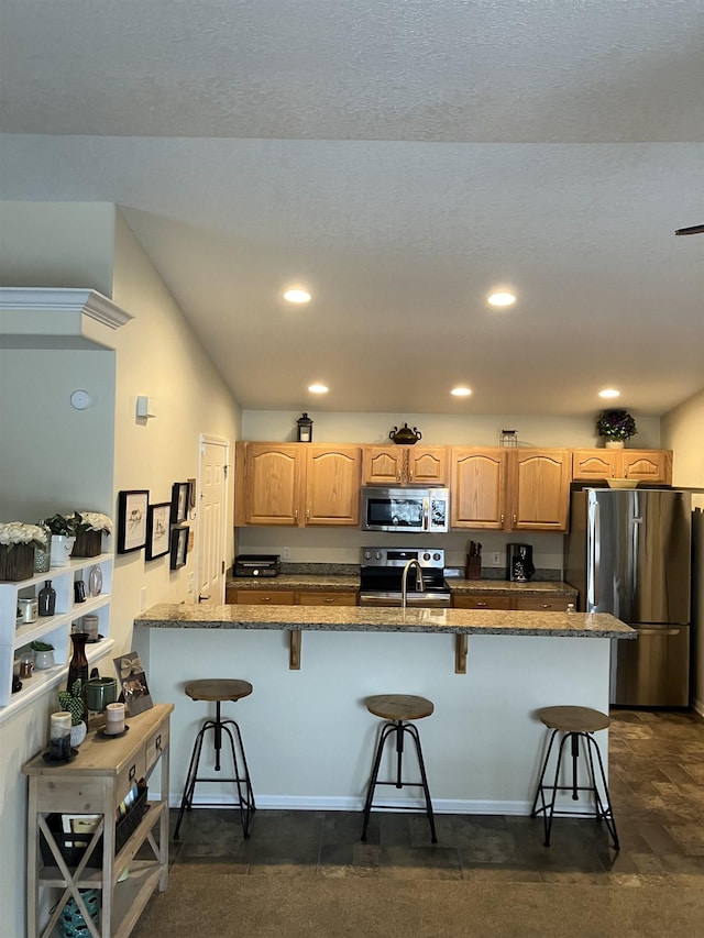 kitchen featuring a sink, appliances with stainless steel finishes, light brown cabinets, and a breakfast bar