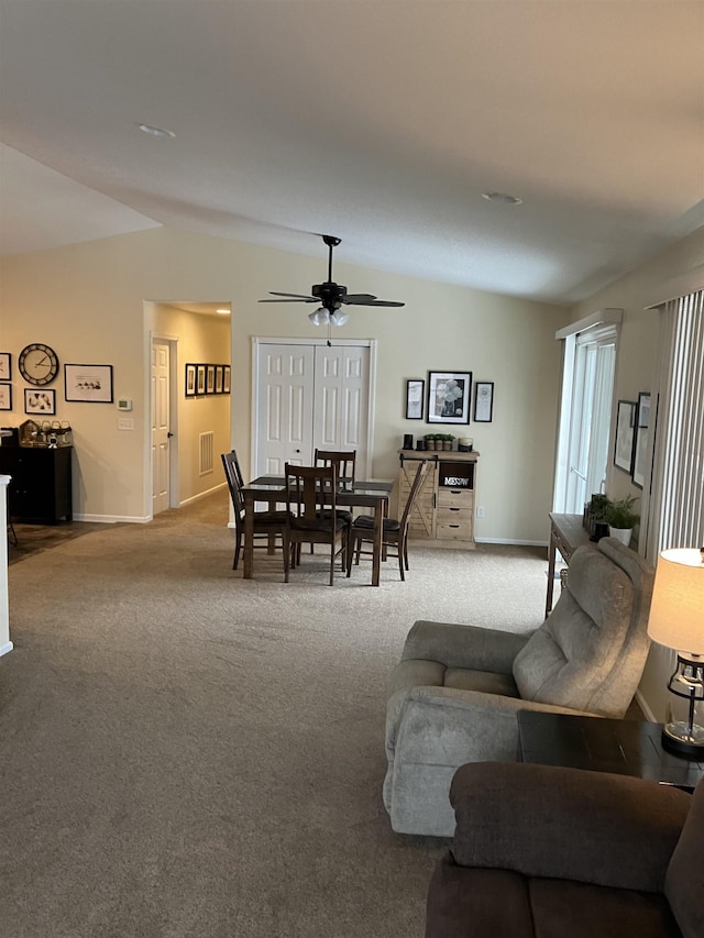 carpeted living room with a ceiling fan, vaulted ceiling, and baseboards