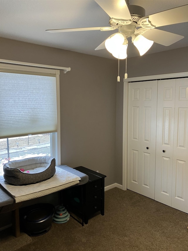 interior space featuring a closet, dark carpet, baseboards, and ceiling fan