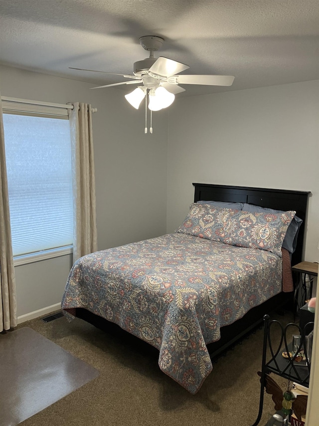 bedroom with a ceiling fan, a textured ceiling, visible vents, and carpet flooring