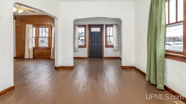 foyer with a ceiling fan, arched walkways, wood-type flooring, and baseboards