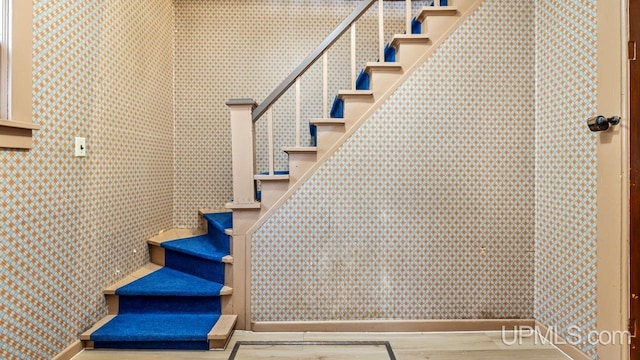 stairs featuring wallpapered walls